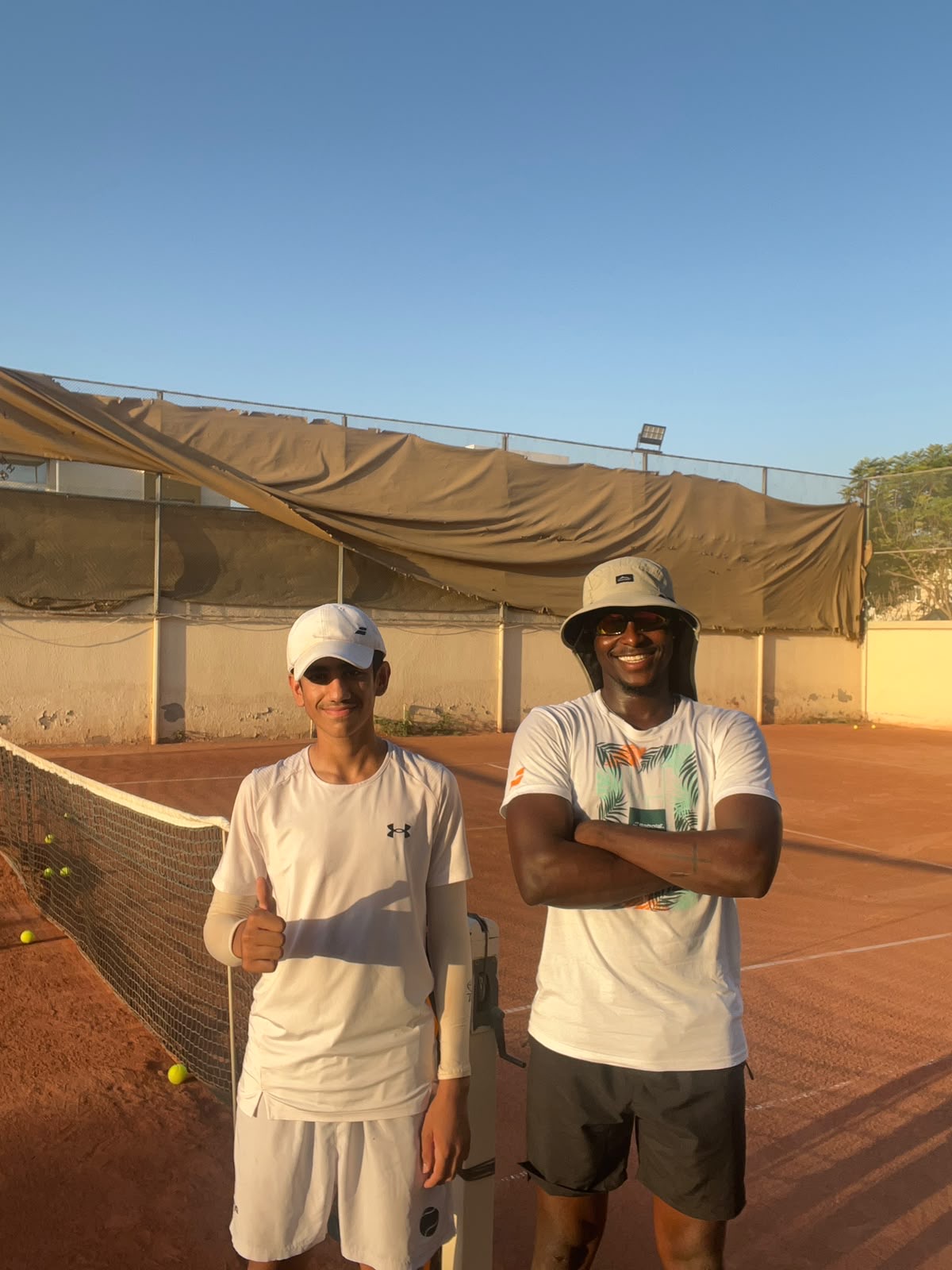 Coach Frank with a junior player on a clay court