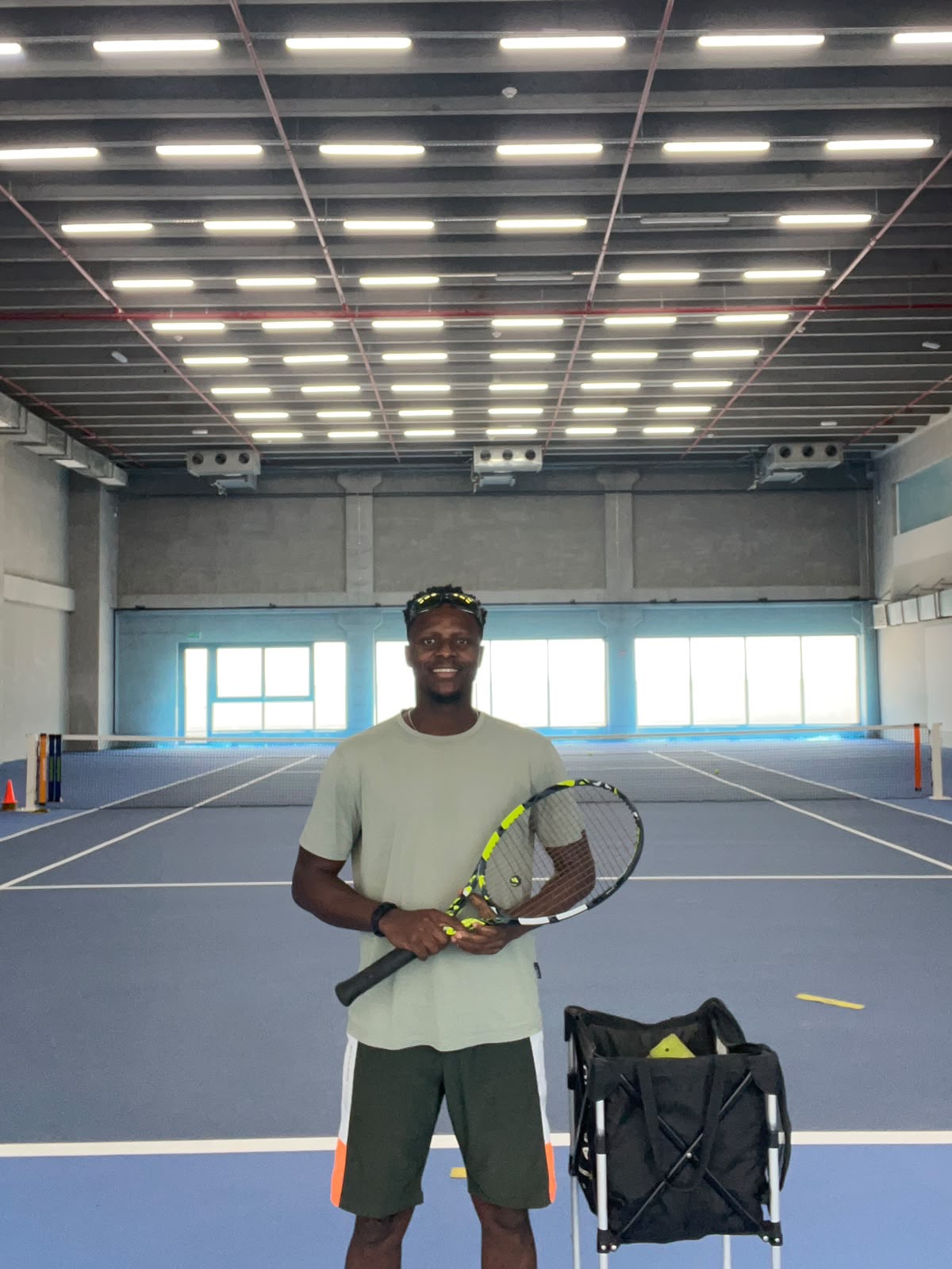 Coach Frank on the indoor court holding a racket